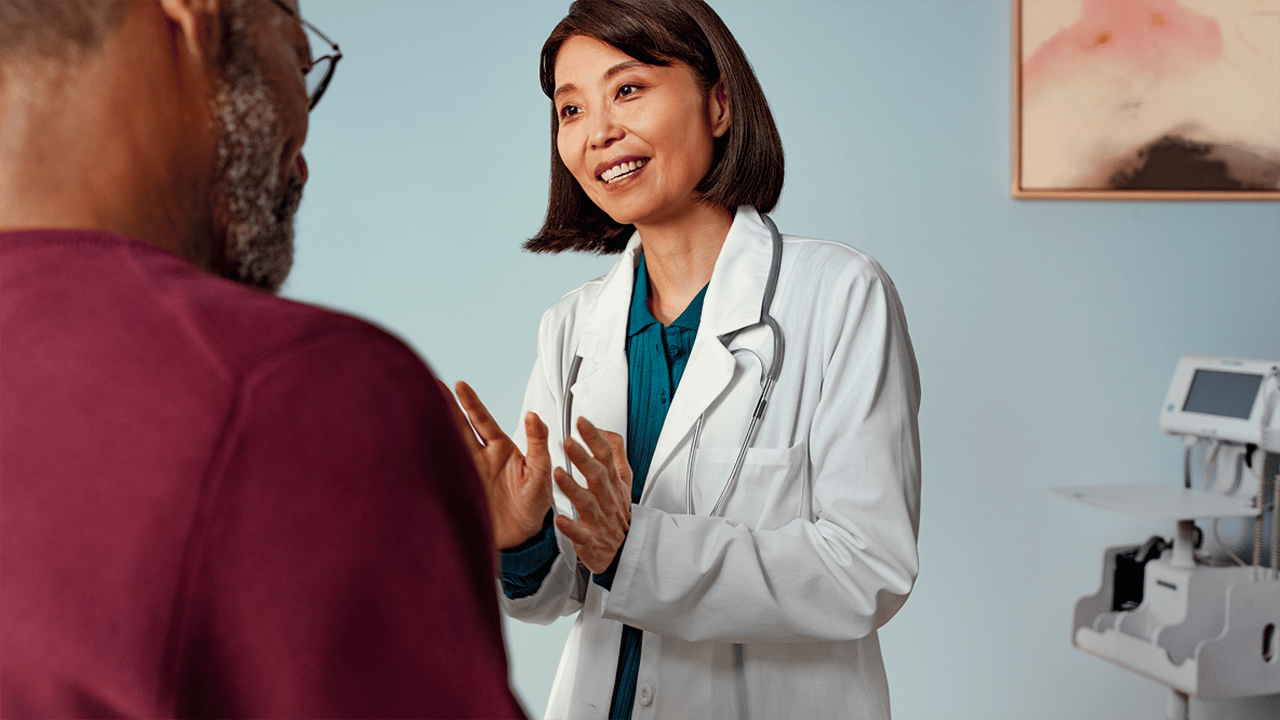 A female healthcare professional in a white coat engages warmly with a patient in a clinical setting. Both appear relaxed and at ease, illustrating the need to ask abything about signs and symptoms