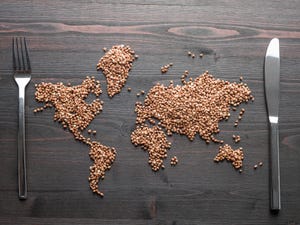 global map representing world hunger or food security on wood table with knife and fork