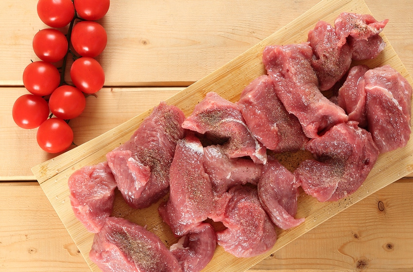 veal raw on cutting board with tomatoes