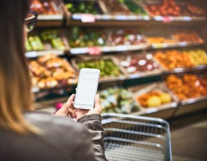 woman grocery shopping while on mobile phone