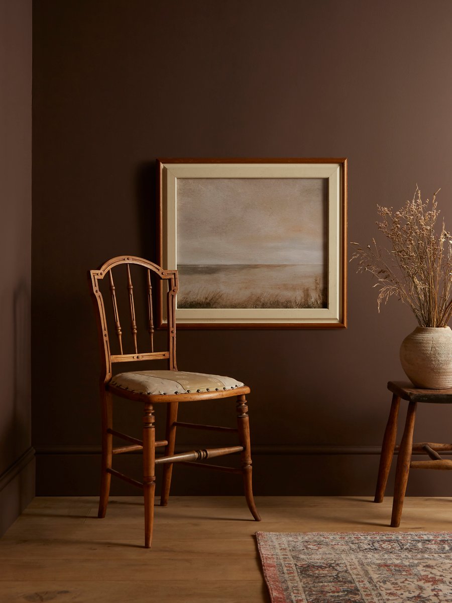 chair and framed artwork next to potted plant with elderton paint on walls 