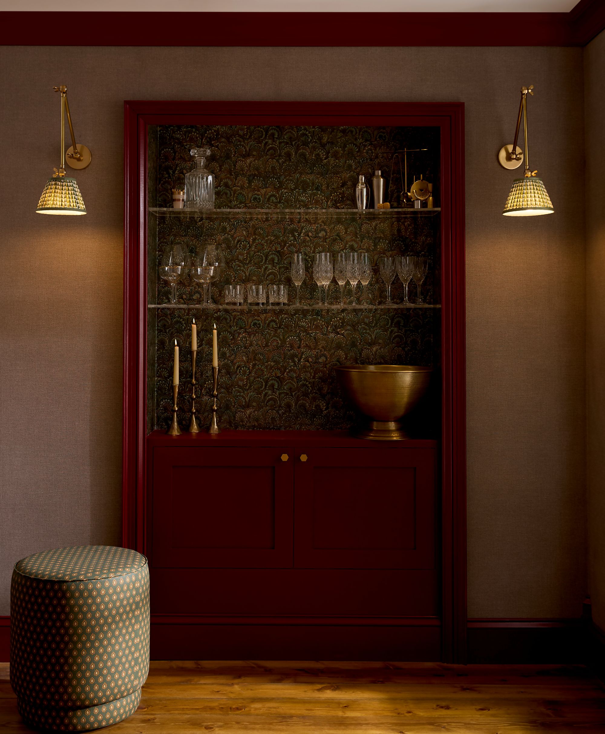 Een barkast in Roger Red interieur eierschaal tegen Truffle Peacock behang, verlicht door twee wandlampen aan weerszijden.