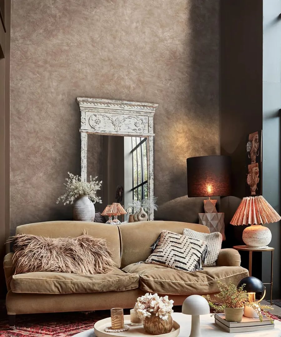 Roomset featuring sofa, lamps and decorated coffee table with Abigail Ahern Urbanite Tadelakt ground wallpaper