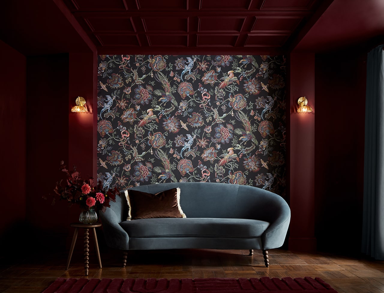 Eternal Weave wallpaper and Divine Damson paint in a living room setting with a blue sofa next to a side table with pink flowers 