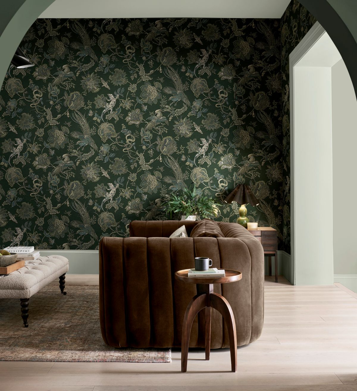 A brown sofa next to a side table with Eternal Weave Emerald wallpaper on the walls 