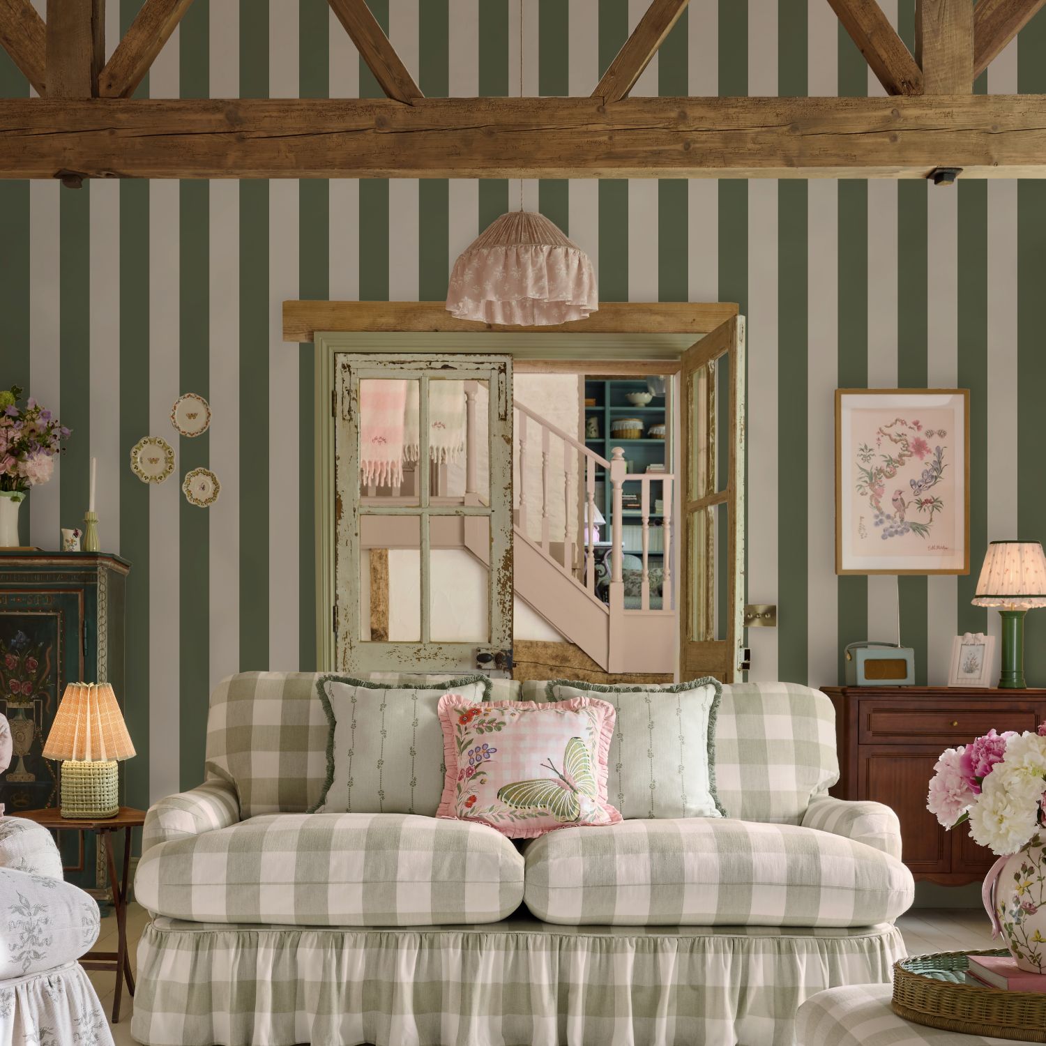 Cath Kidston Canopy Stripe Vintage Green Roomset with a check fabric settee in a lounge with wooden ceiling beams and a staircase peeking through a glass door.