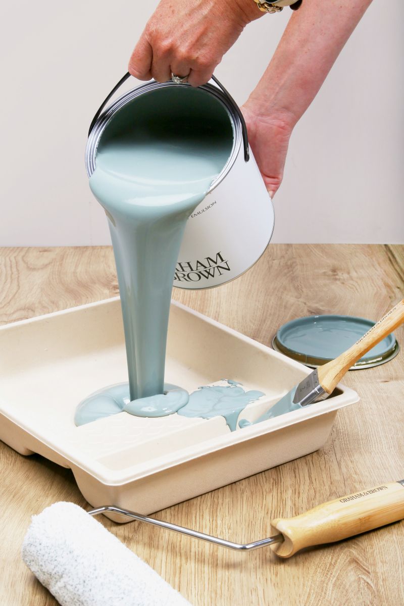 Paint kit contents arranged neatly, including brush, roller frame, roller sleeves, paint tray, can opener and washi tape.
