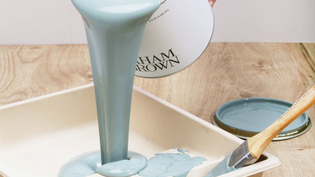Paint kit contents arranged neatly, including brush, roller frame, roller sleeves, paint tray, can opener and washi tape.