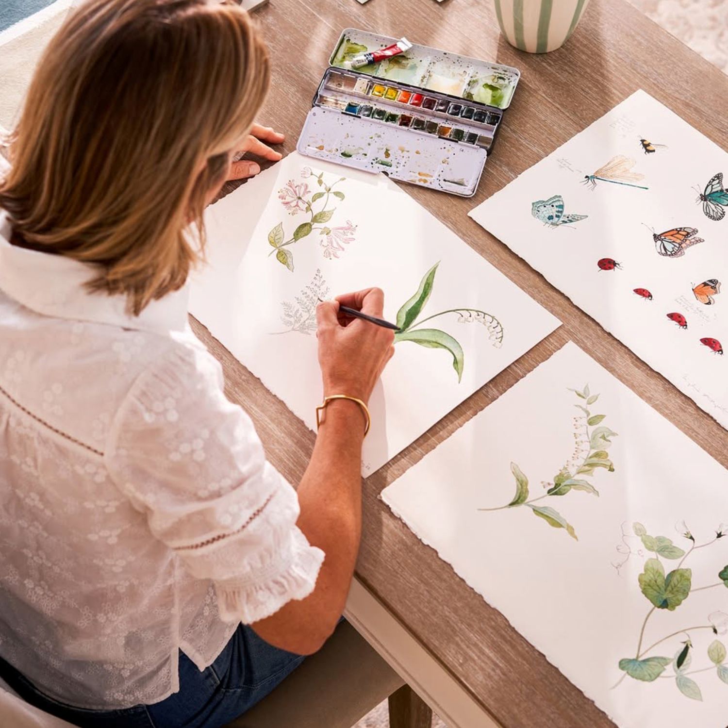 Sophie Allport drawing artwork of plants and butterflies at a desk