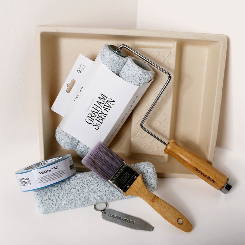 Paint kit contents arranged neatly, including brush, roller frame, roller sleeves, paint tray, can opener and washi tape.