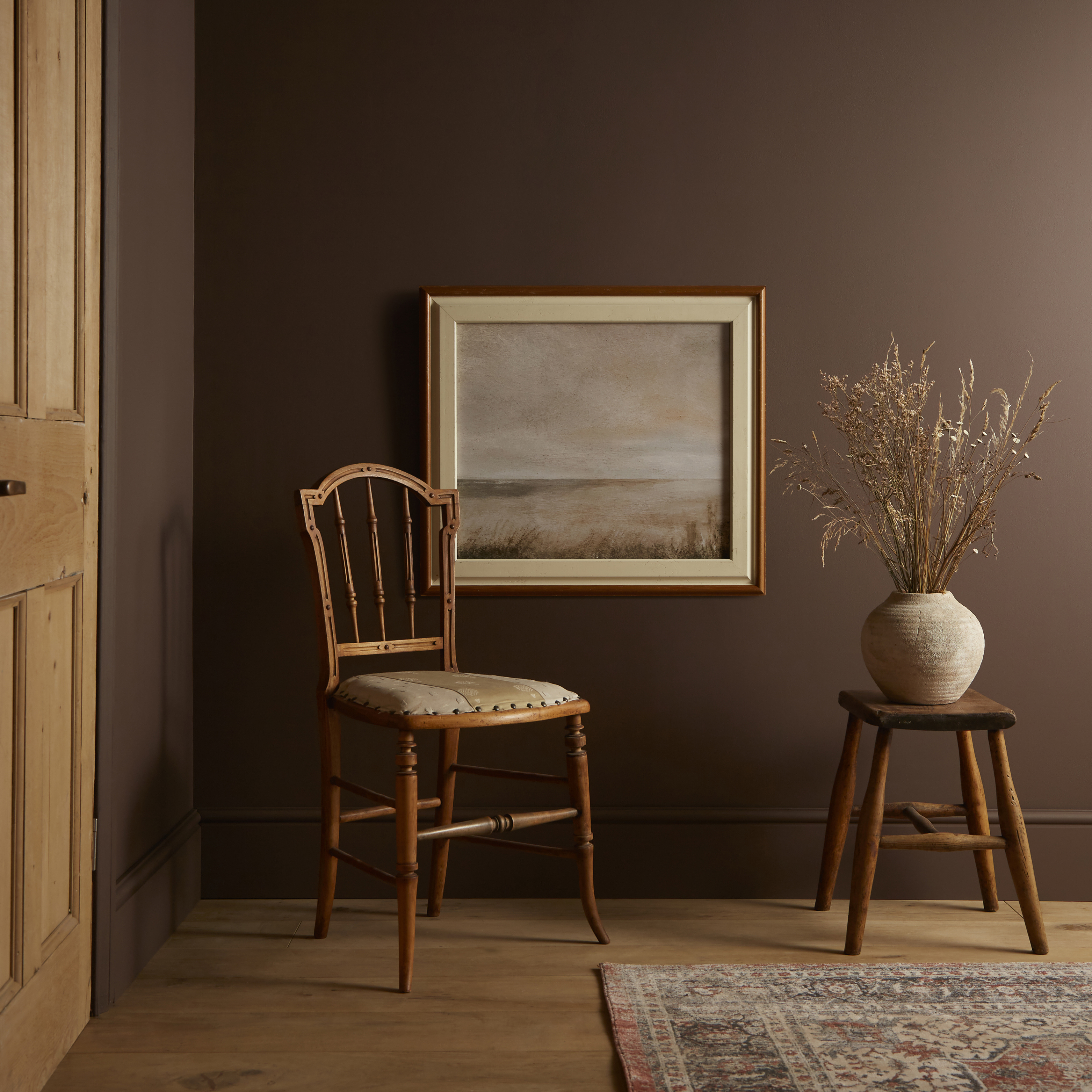 chair and framed artwork next to potted plant with elderton paint on walls 