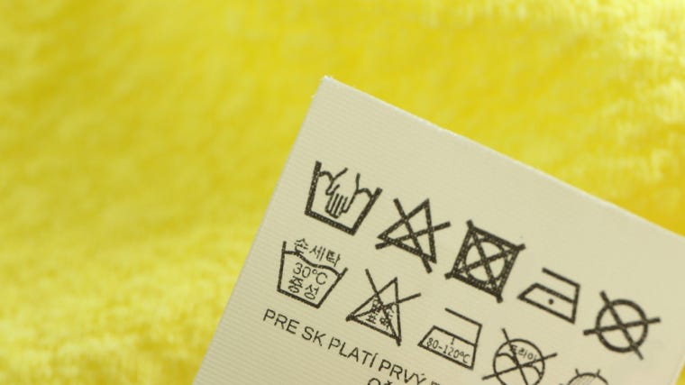 A zoomed in photo of a clothing label with a hand wash symbol