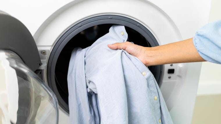 A person loading a washing machine with clothes