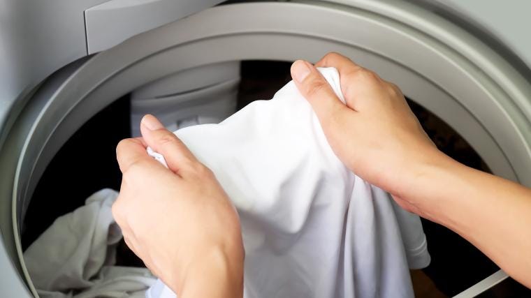 Person loading white clothes in to a washing machine