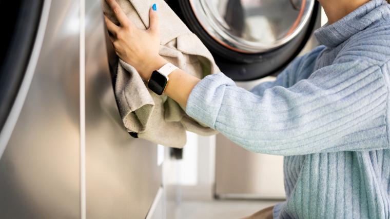 A person loading a washing machine with clothes