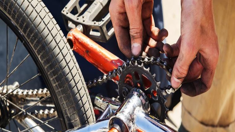 A person fixing a bike chain with grease on clothes