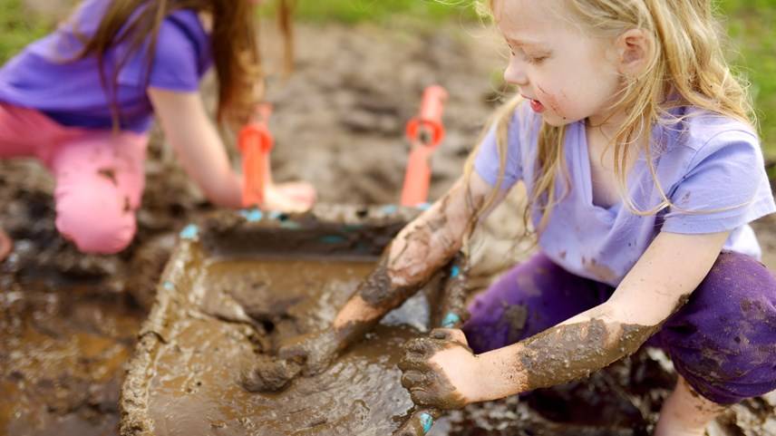 Par de niñas con playeras moradas juegan en lodo