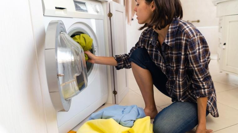 A person loading a washing machine with clothes