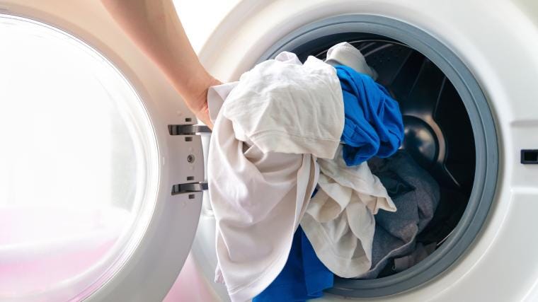 A person loading a washing machine with clothes