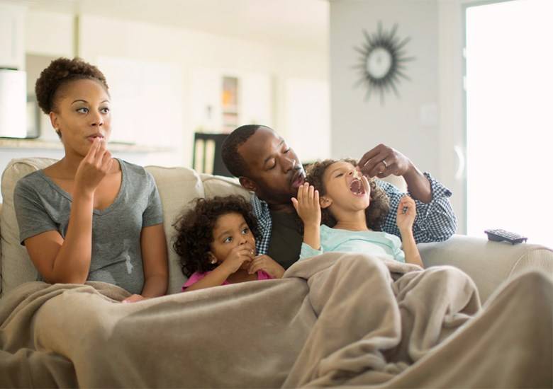 Familia convive en sillón con cobija mientras comen