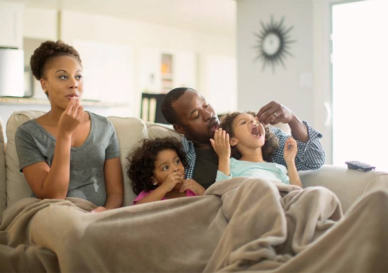 Familia comiendo en un sillón de casa