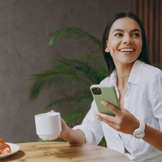 Mujer tomando café sosteniendo movil