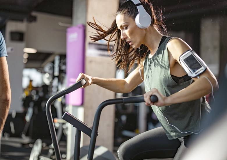 Mujer escuchando música y haciendo ejercicio en gimnasio