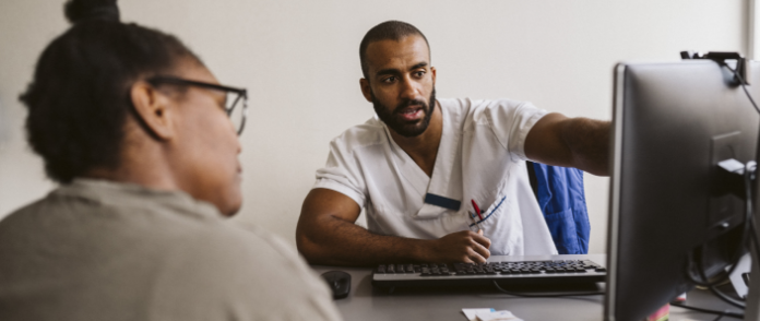 A healthcare professional showing a patient something on a computer