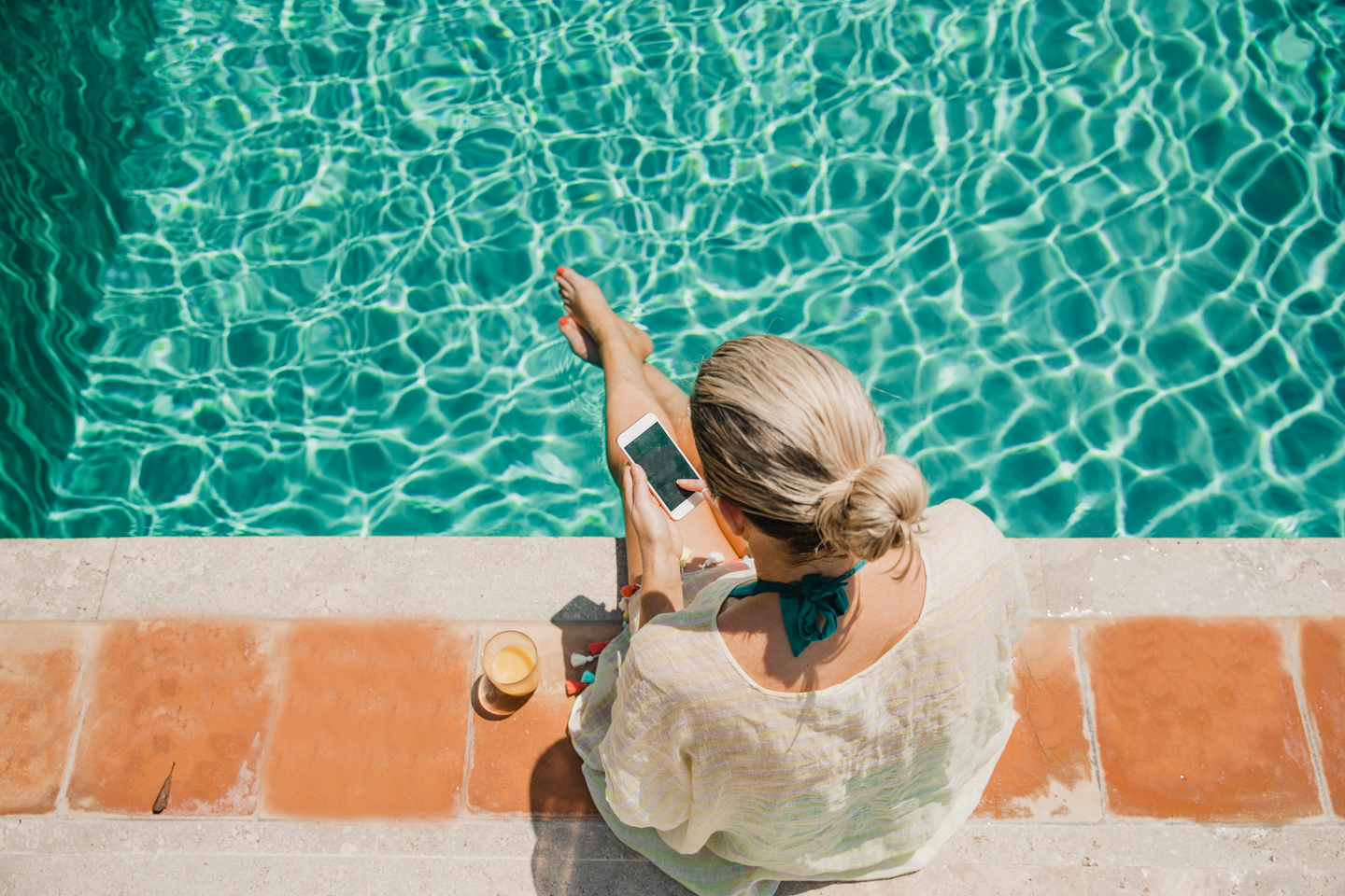 Frau mit Handy am Pool