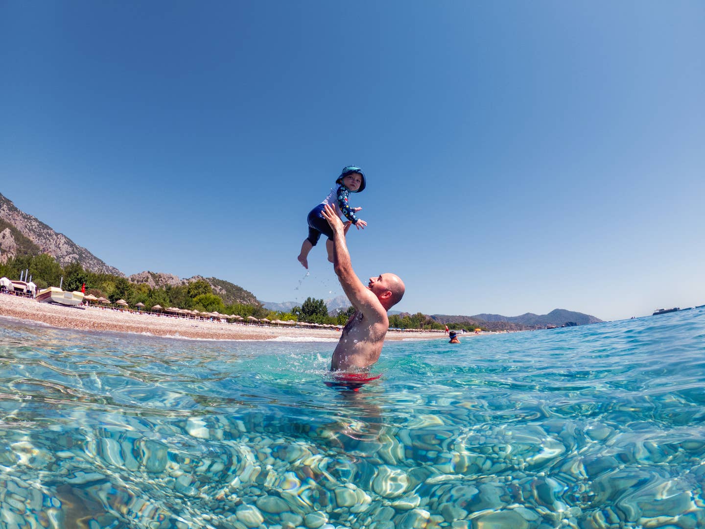 Mann spielt mit Kind im Meer