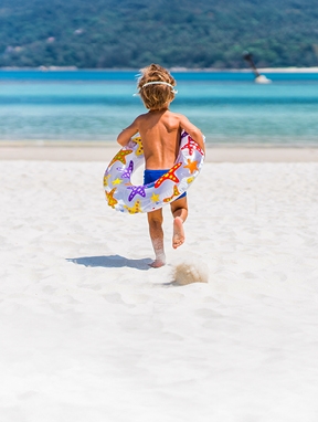 Junge mit Schwimmring am Strand
