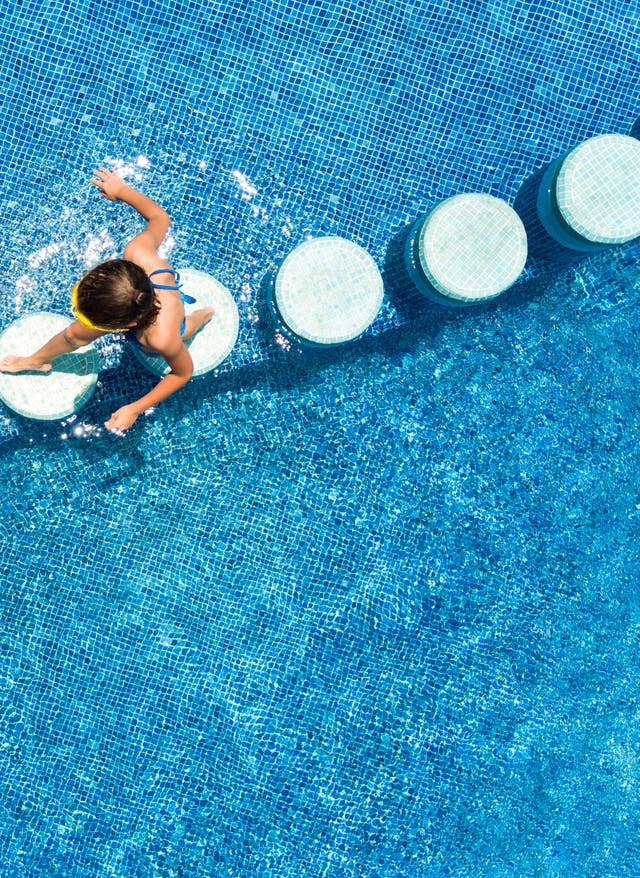Brückentage Kinder laufen über Trittsteine im Pool