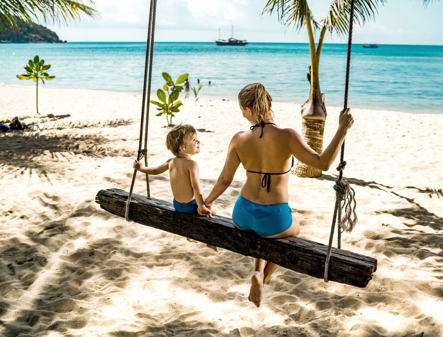 Mutter mit Kind am Strand auf einer Schaukel