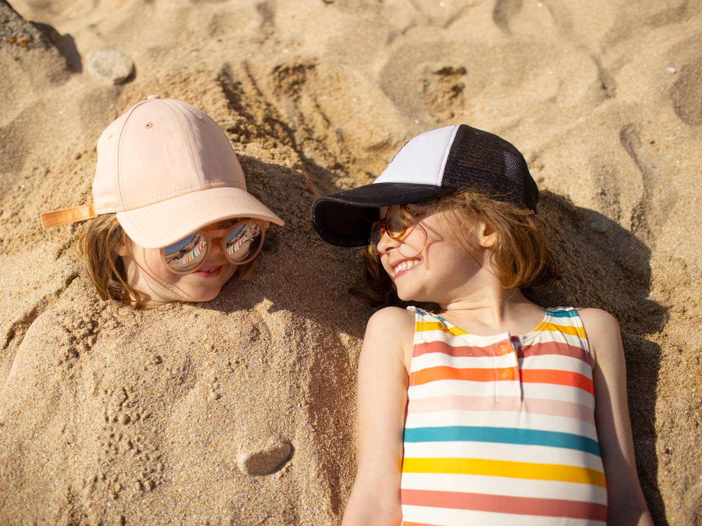 Kinder liegen am Strand im Sand