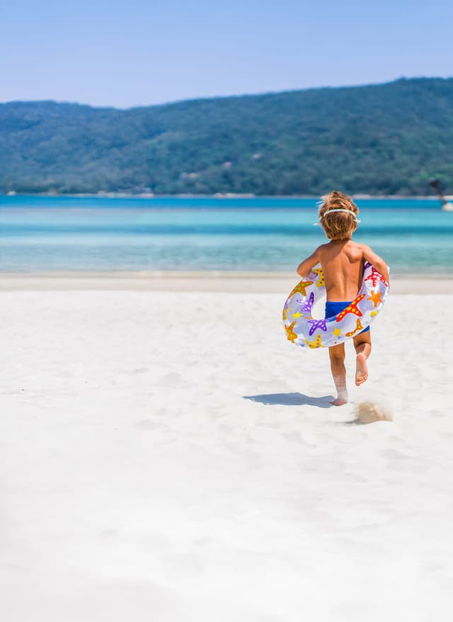 Osterurlaub Kind mit Schwimmring am Strand