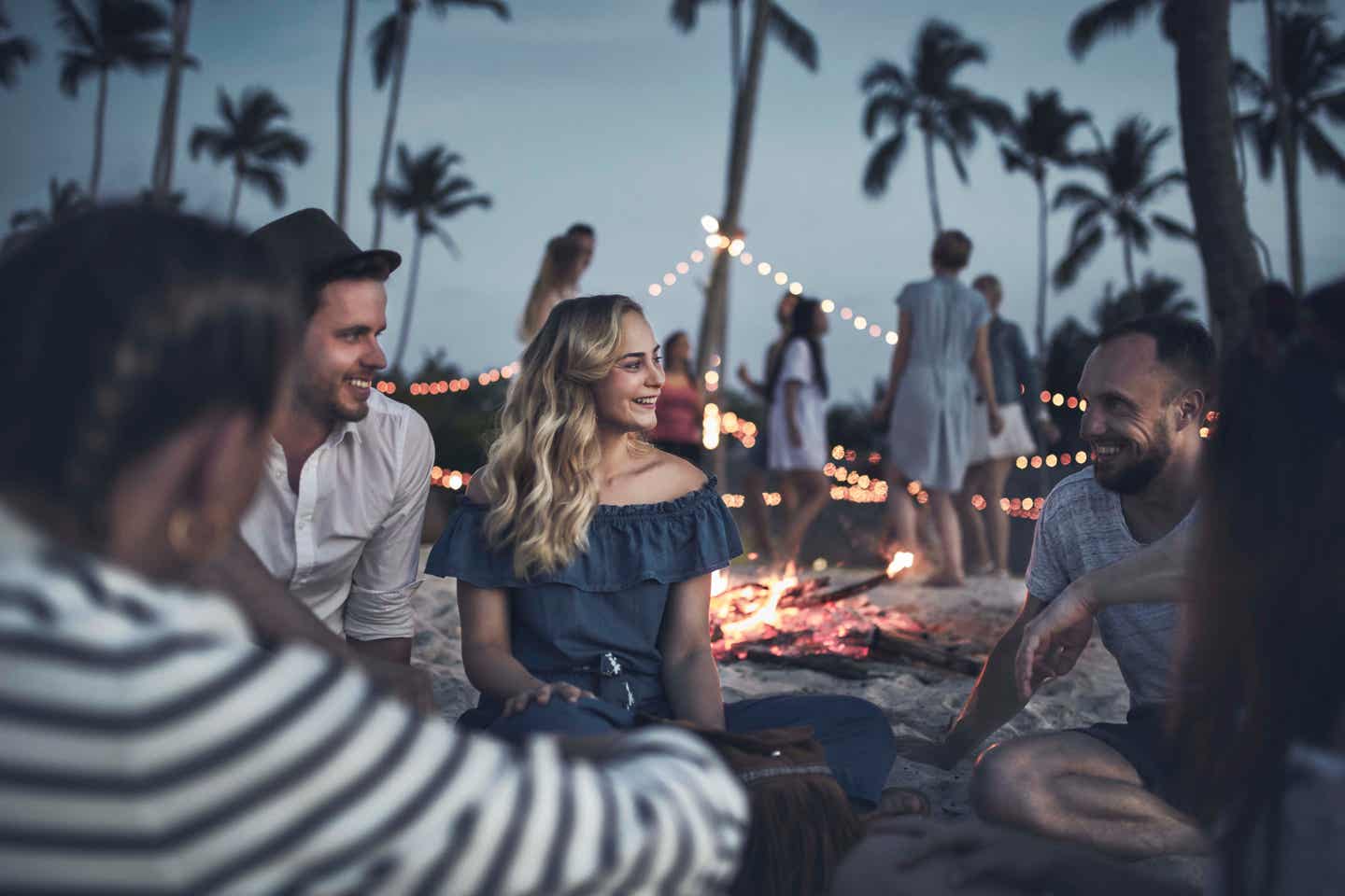 Gruppe von Freunden sitzt am Lagerfeuer am Strand