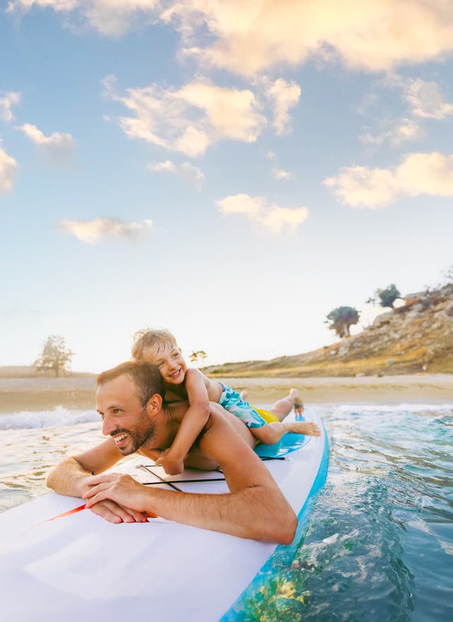 Frühbucherangebote Vater und Sohn auf einem Surfboard