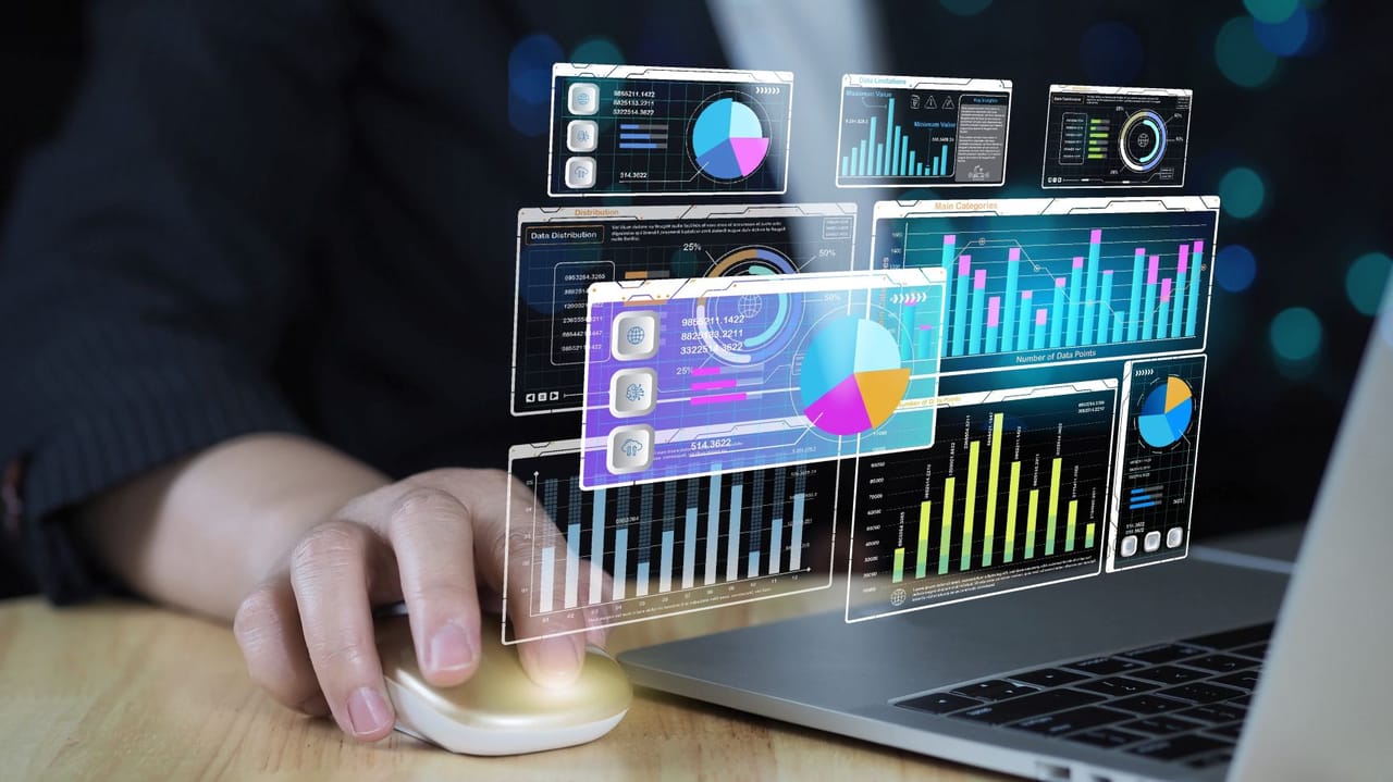 An image of a person at a laptop with data graphics floating in front An image of a person at a laptop with data graphics floating in front