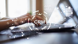 An image of a person at a laptop with the words CRM hovering over their hands An image of a person at a laptop with the words CRM hovering over their hands
