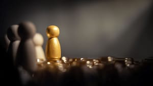 An image of wooden people with one under a spotlight An image of wooden people with one under a spotlight