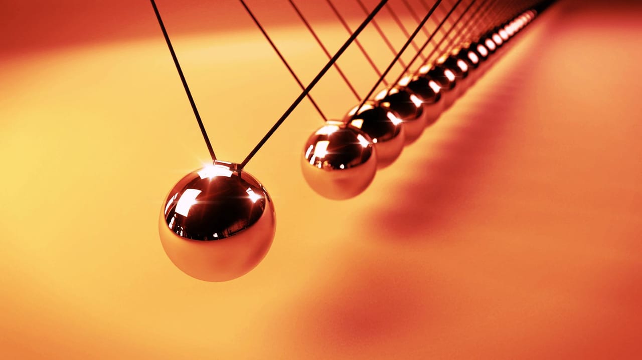 An image of pendulum balls on an orange background An image of pendulum balls on an orange background
