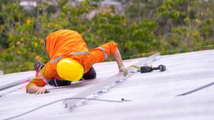 A worker inspecting a metal roof A worker inspecting a metal roof