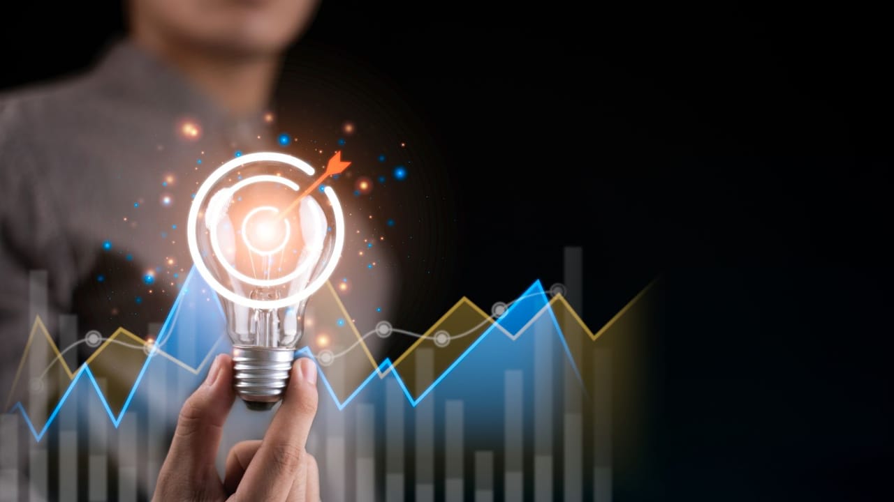 A hand holding a light bulb with a clear bullseye sitting over the top of it A hand holding a light bulb with a clear bullseye sitting over the top of it