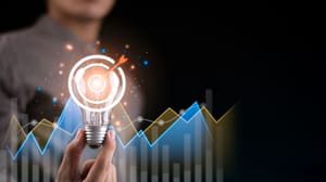 A hand holding a light bulb with a clear bullseye sitting over the top of it A hand holding a light bulb with a clear bullseye sitting over the top of it