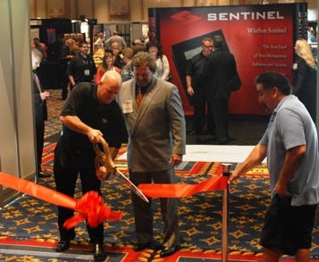Troy Bix, vice president of Inside Self-Storage, looks on as Jon Reddick, president of Sentinel Systems Corp., cuts the ceremonial ribbon at the opening of the ISS Exhibit Hall on April 3.