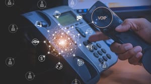 Hand of man using IP phone with flying icon of VoIP services Hand of man using IP phone with flying icon of VoIP services