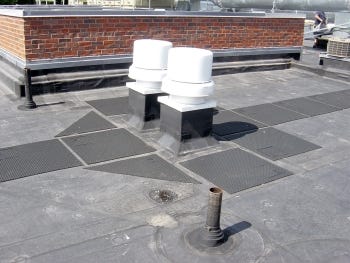 An EPDM membrane is fully adhered to a coverboard over the primary insulation. The walk pads are a protective layer for foot traffic and tools or equipment placed on the roof during maintenance of the mechanical vents.