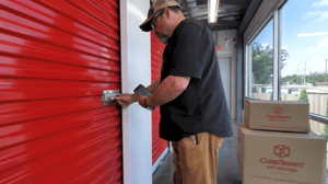 An image of a male customer opening the red door to his climate-controlled self-storage unit using a mobile app An image of a male customer opening the red door to his climate-controlled self-storage unit using a mobile app