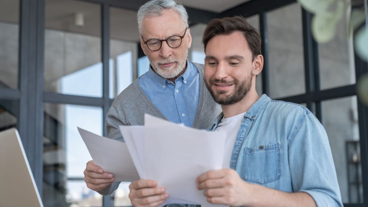 A father and son looking at paperwork A father and son looking at paperwork