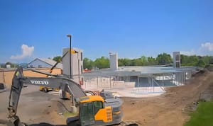 A building under construction with a backhoe sitting in front of it A building under construction with a backhoe sitting in front of it
